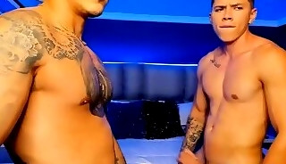 Tattooed and muscular gay couple masturbate in sync